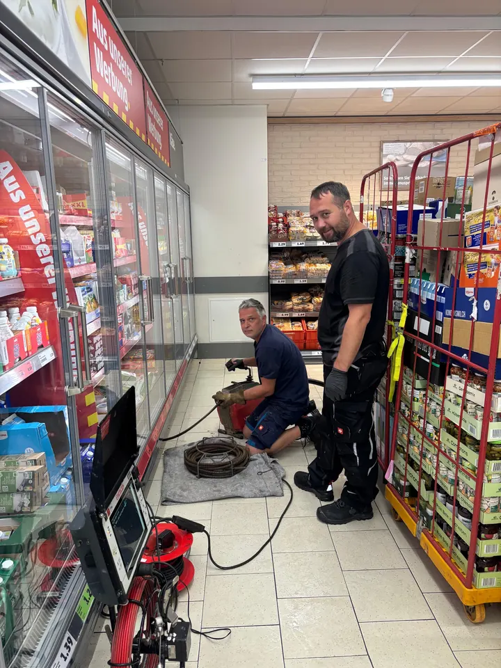 Zwei Monteure von E.N. bei einer Kamerabefahrung im Supermarkt, Livebild auf dem Monitor