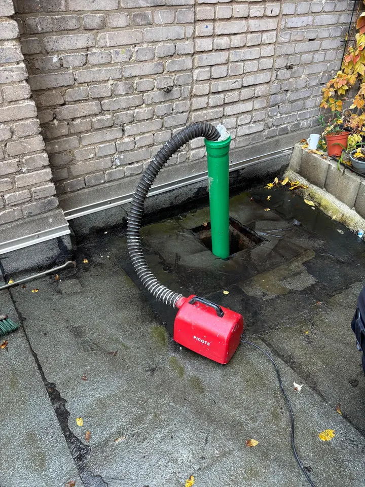 Schlauch der Reinigungsanlage im geöffneten Hofablauf